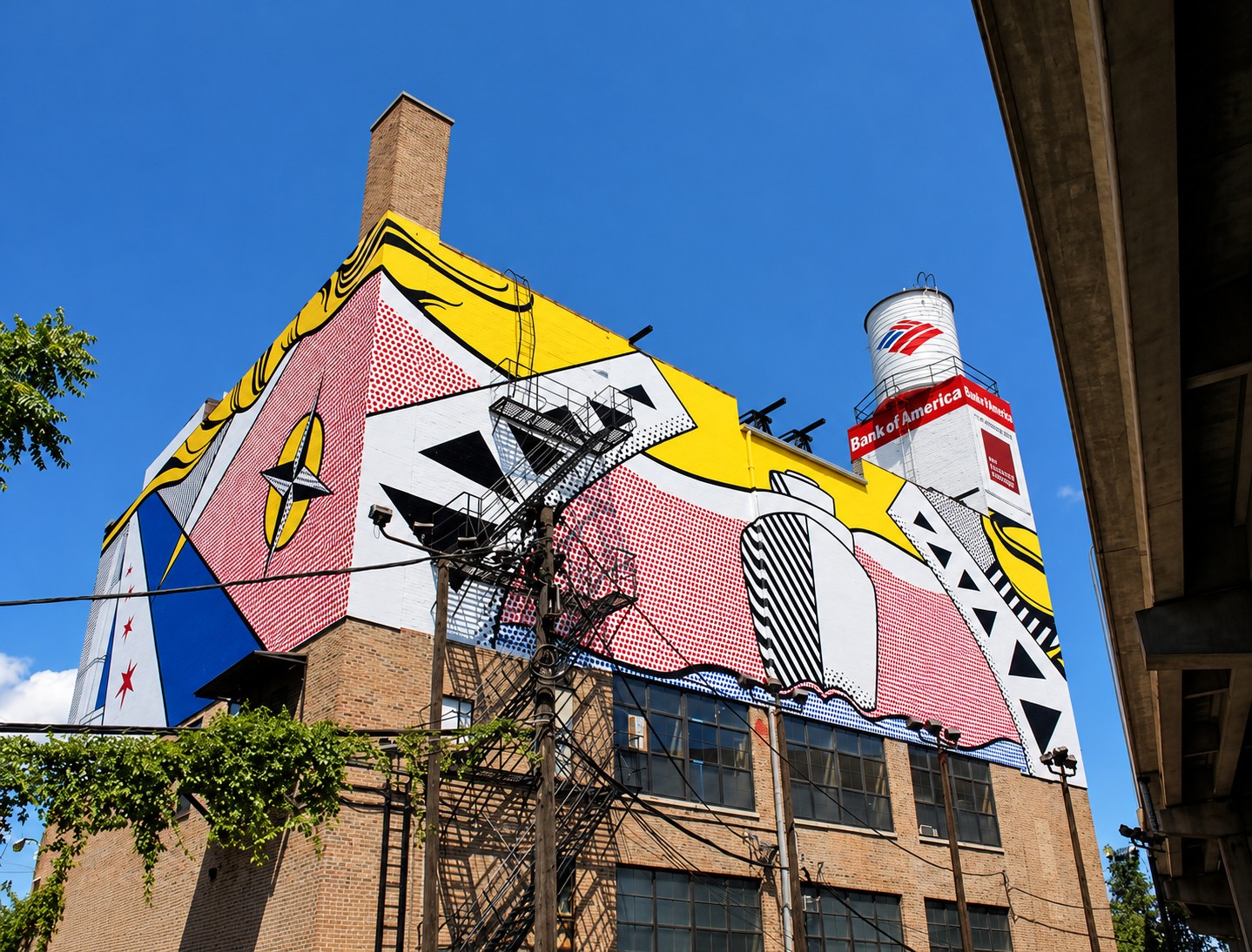 The full building from the street: the Lichtenstein mural across the whole facade, water tower above