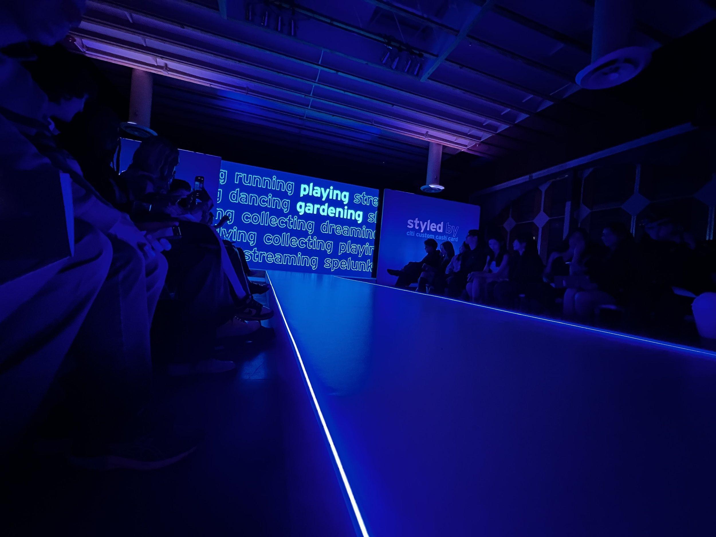 The runway before the show, lit blue, with the spending categories scrolling on the screen